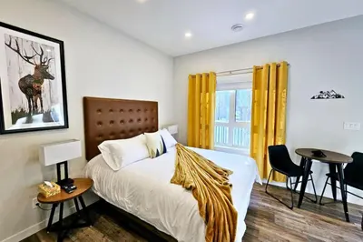 a bedroom with a bed and a table and yellow curtains at Cloudline Vista 3 BdrmTownhouse with Garage managed by Little Sister Getaways in Canmore
