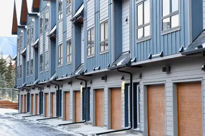 a row of blue and white buildings on a street at Cloudline Vista 3 BdrmTownhouse with Garage managed by Little Sister Getaways in Canmore