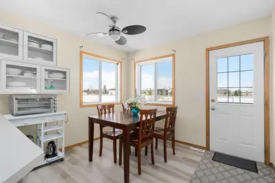 a dining room with a table and chairs and windows at Peacock Suites in Airdrie