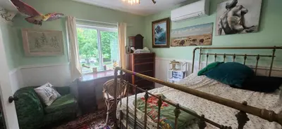a bedroom with a bed and a chair and a window at Trout House by Trout Lake in Vancouver