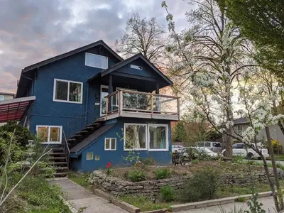 a blue house with a balcony on top of it at Garden View double room suite at Trout Lake in Vancouver
