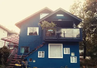 a blue house with a balcony on top of it at Garden View double room suite at Trout Lake in Vancouver