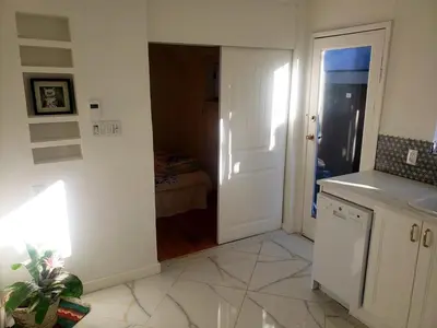 a kitchen with a door leading to a bedroom at Garden View double room suite at Trout Lake in Vancouver