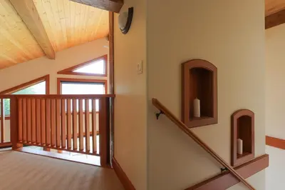 a staircase in a house with a wooden railing at Custom Built Home on the Beach in Nelson