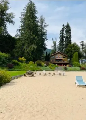 a beach with a blue bench and a house at Custom Built Home on the Beach in Nelson