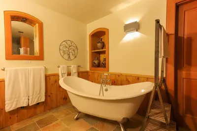 a bath tub in a bathroom with wooden walls at Custom Built Home on the Beach in Nelson