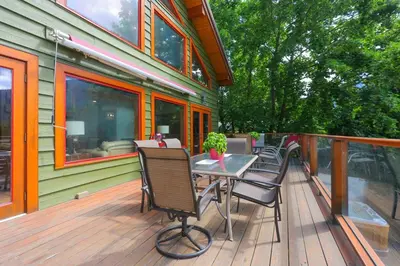 a deck with a table and chairs on a house at Custom Built Home on the Beach in Nelson