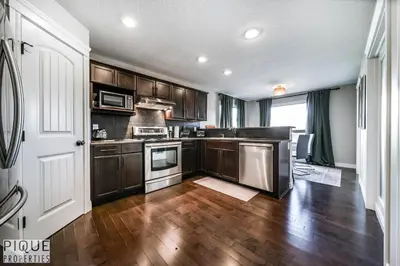 a kitchen with wooden cabinets and a hard wood floor at 5BD Jungle Oasis - HotTub - BBQ - King Bed - Games - Garage in Edmonton