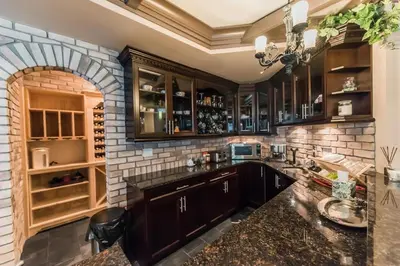 a kitchen with wooden cabinets and a brick wall at Grace Guest House in White Rock