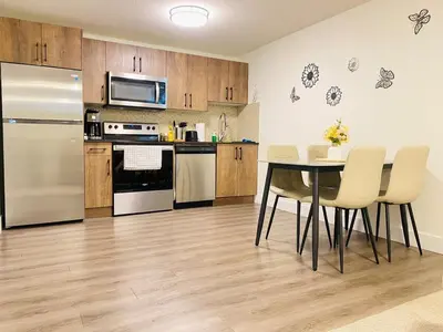 a kitchen with a table with chairs and a refrigerator at Modern Cozy Entire Guest Suite in Central Edmonton in Edmonton