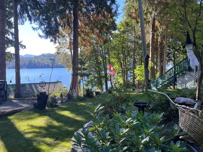 a garden with a view of the water and trees at Mile 77 Cottages in Youbou