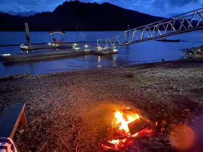 a fire on the beach with a bridge at Mile 77 Cottages in Youbou