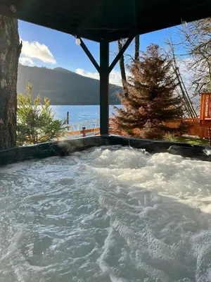 a jacuzzi tub with a view of the water at Mile 77 Cottages in Youbou