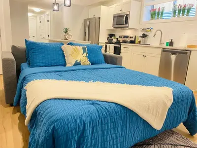 a blue bed in a room with a kitchen at The Private Central Edmonton Suite - Comfortable & Fully-Equipped Basement Suite in Edmonton