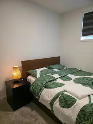 a bedroom with a bed and a table with a lamp at Cozy 2 Bedroom Apartment in Calgary