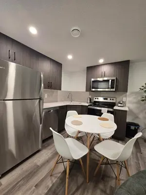 a kitchen with a table and chairs and a refrigerator at Cozy 2 Bedroom Apartment in Calgary