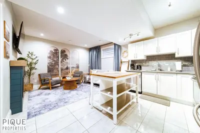 a kitchen and living room with white cabinets and a table at Chic Retreat with Hot Tub - King Bed - Fireplace - WEM in Edmonton