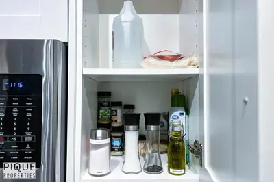 a cupboard filled with bottles and containers next to a refrigerator at Chic Retreat with Hot Tub - King Bed - Fireplace - WEM in Edmonton