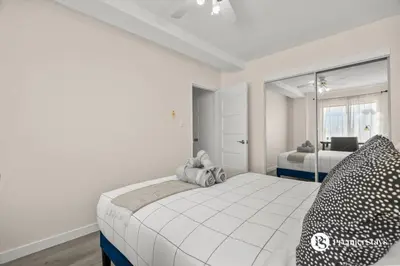a white bedroom with a bed and a window at Downtown 17th Ave Lifestyle with Secure Parking and AC in Calgary