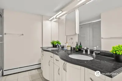 a bathroom with two sinks and a large mirror at Downtown 17th Ave Lifestyle with Secure Parking and AC in Calgary