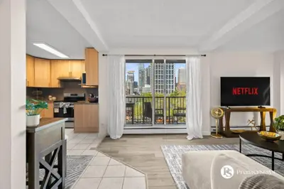 a kitchen and living room with a view of a city at Downtown 17th Ave Lifestyle with Secure Parking and AC in Calgary