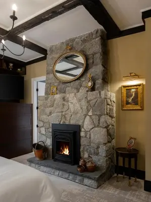 a stone fireplace in a bedroom with a mirror at Rosemead House in Victoria