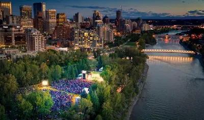 a large crowd of people standing next to a river at Riverside Retreat - FREE Banff Pass, Gym, Parking! in Calgary