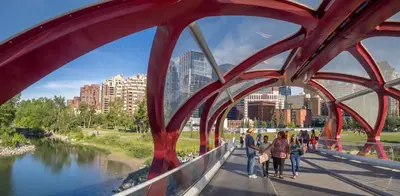 a group of people walking on a bridge over a river at Riverside Retreat - FREE Banff Pass, Gym, Parking! in Calgary