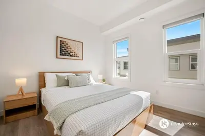a white bedroom with a bed and two windows at Executive Suite with King Bed Garage AC Free Banff Pass 65 Inch TV in Calgary