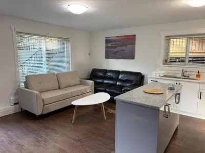 a kitchen and living room with a couch and a table at Private two bedroom basement suite Sleeps six people in Surrey