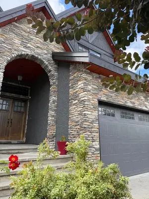 a brick house with a garage door and flowers at Private two bedroom basement suite Sleeps six people in Surrey