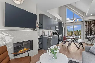 a living room with a fireplace and a kitchen at Peak n Plunge Insane MTN View Pool n Hot Tub K201 in Canmore