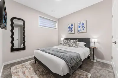 a white bedroom with a bed and a mirror at Classic 2 Bed-Basement Near the lake in Edmonton
