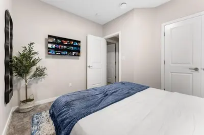 a bedroom with a white bed with a blue blanket at Classic 2 Bed-Basement Near the lake in Edmonton