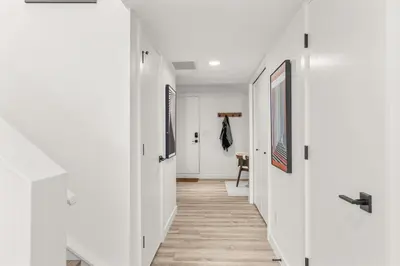 a hallway with white walls and wood floors at 3BR Escape BBQ, Balcony, Near Banff & DT in Canmore