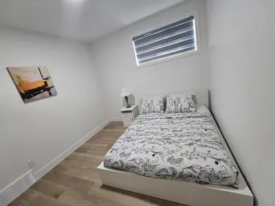 a white bedroom with a bed and a window at Lush 1 Bedroom house with WiFi in Edmonton in Edmonton