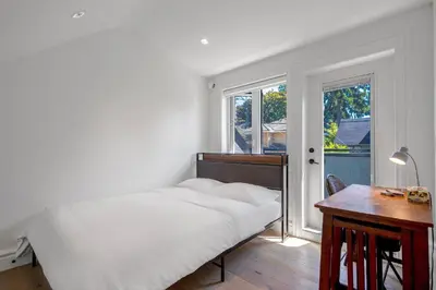 a bedroom with a bed and a desk and a window at Dunbar Brand-new laneway house in Vancouver