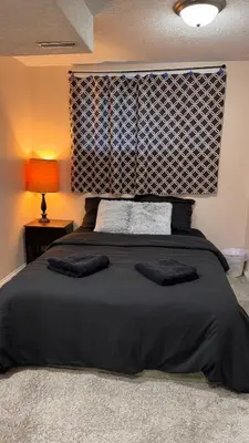 a bedroom with a black bed with two pillows at Calgary Super Cozy Guest Rooms Near Banff in Calgary