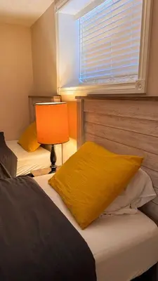 a bedroom with two beds with a lamp and a window at Calgary Super Cozy Guest Rooms Near Banff in Calgary
