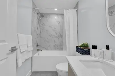 a white bathroom with a shower and a toilet at Basement in Calgary - 10 Mins from Calgary Airport in Calgary