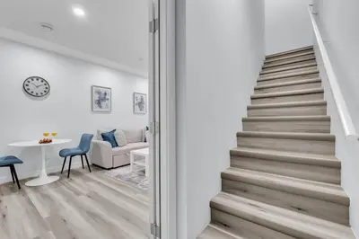a staircase leading up to a living room with a table at Basement in Calgary - 10 Mins from Calgary Airport in Calgary