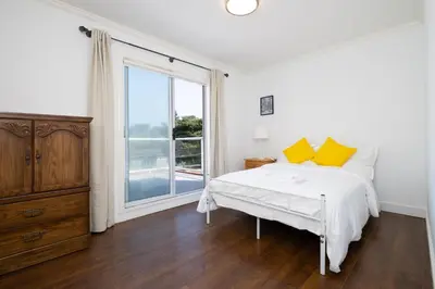 a white bedroom with a bed and a large window at Elegant Spanish Villa with Ocean & Mountain Views in Vancouver
