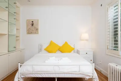 a white bedroom with a white bed with yellow pillows at Elegant Spanish Villa with Ocean & Mountain Views in Vancouver