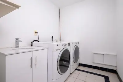 a white laundry room with a washer and a sink at Elegant Spanish Villa with Ocean & Mountain Views in Vancouver