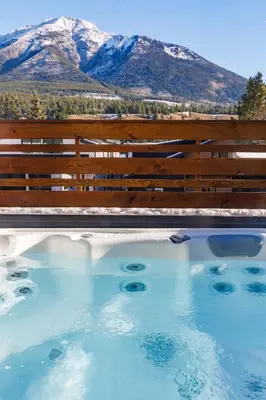 a swimming pool with a fence and mountains in the background at Aurora Luxe - Stunning Townhouse Private Hot Tub in Canmore