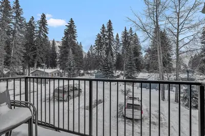 a balcony with a snow covered yard with two cars at banff woods lodge in Canmore