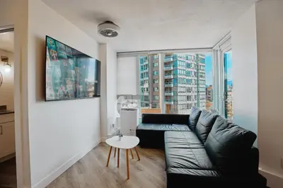 a living room with a couch and a large window at Cozy Urban Living! 2 mins from BC place, private parking ! in Vancouver