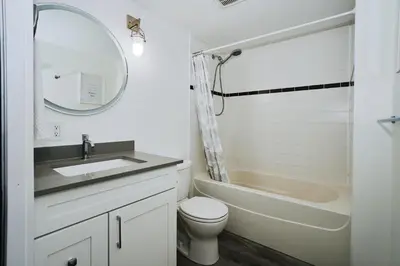 a bathroom with a sink and a toilet and a mirror at Cozy Urban Living! 2 mins from BC place, private parking ! in Vancouver