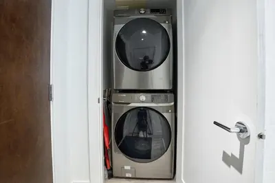 two washing machines sitting inside of a door at Cozy Urban Living! 2 mins from BC place, private parking ! in Vancouver