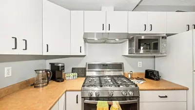 a kitchen with white cabinets and a stove top oven at Knockan Hill Rentals - Ground Floor Suite in Victoria